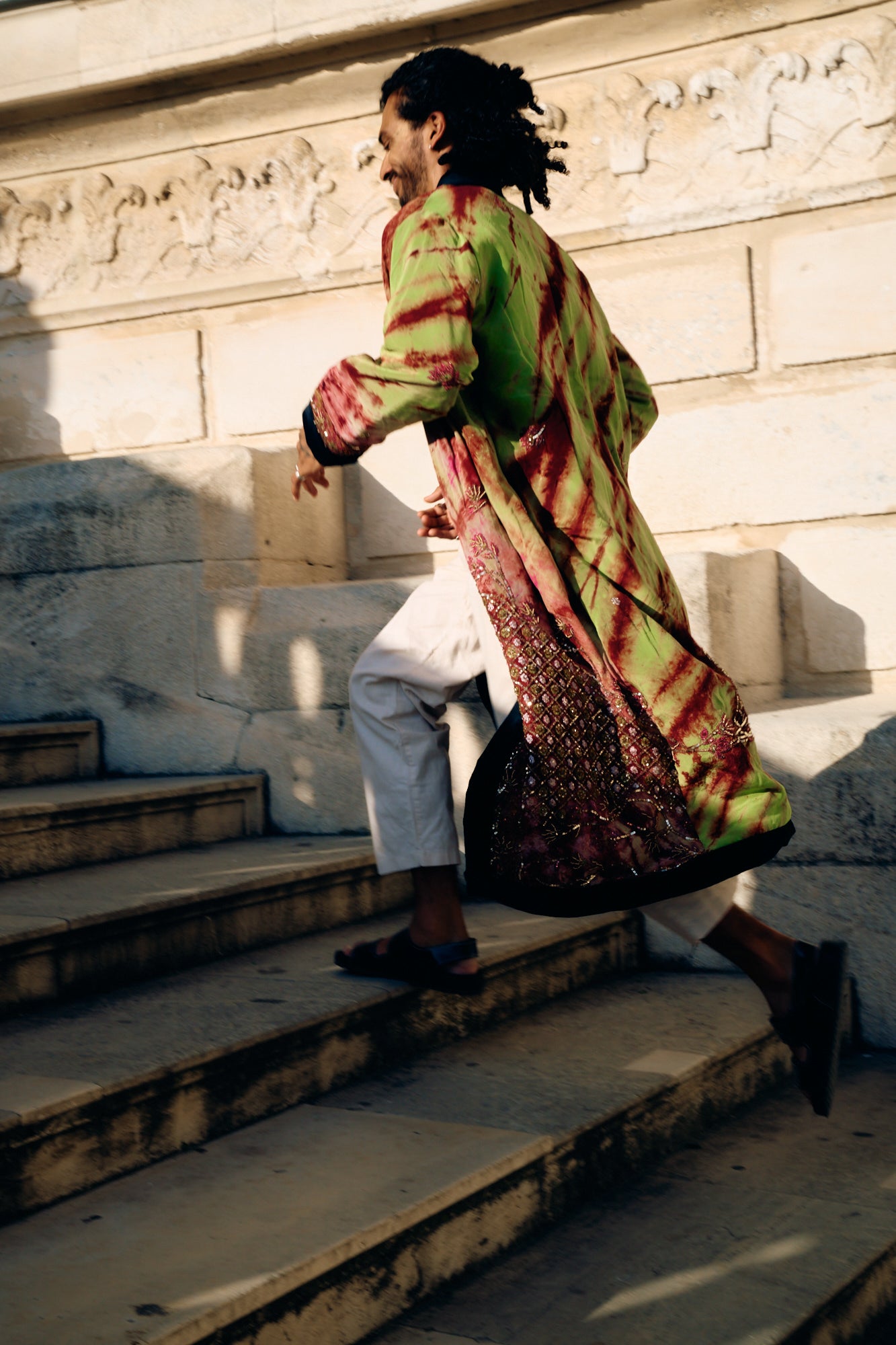 Male model running in the stairs wearing a long sleeves coat with pure silk and hand-made embroideries unique piece by Yayavara Creation